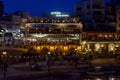 People relaxing at illuminated St. Julian`s coastline at night, near restaurants and cafe