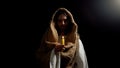 Saint man holding candle, praying for people sins expiation, belief and kindness