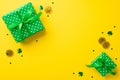 Top view photo of green gift boxes in wrapping paper with polka dot pattern and bows gold coins and trefoil shaped confetti