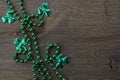 Saint Patrick's day frame with green beads and shamrock on wooden background. Royalty Free Stock Photo