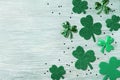 Saint Patricks Day background with green shamrock on white rustic board top view.