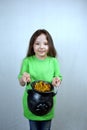 Saint Patricks Day celebration motif. Adorable smiling seven years old girl show cast iron leprehauns pot full of gold
