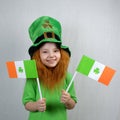 Saint Patricks Day. Endearing smiling little girl with decorative red beard, dressed in green, in leprechaun\'s hat