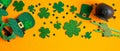Saint Patricks Day frame border of shamrock four leaf clovers, Irish elf hat, pot of gold, party glasses on orange background. Royalty Free Stock Photo