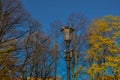 Saint Petersburg city park in sunset light. Old vintage black decorative lantern with glass lamps on pillar, pole in bright spring Royalty Free Stock Photo