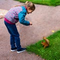 Little girl feeds a squirrel in a park in summer
