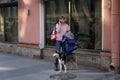 A young woman with a dog is standing on the sidewalk and talking on the phone
