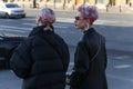 Two young fashionable girls walk along a street in the center of the city