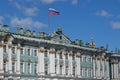 Sunny day in Saint-Petersburg, russian flag flying above facade of Hermitage State Museum