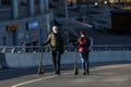 Saint-petersburg, Russia - 4 April 2020: A young couple in masks with electric scooters walk up the Yakhtenniy bridge