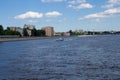 Boat on a wide river, against the backdrop of the city landscape and blue sky with clouds