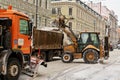 The tractor loads the cleaned snow on the dump truck