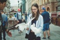 Girl teenager walks on the street of St. Petersburg, holds in the hands of white pigeons