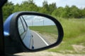 Rural lanscape country road is reflected in side mirror of car during the summer trip perspective from automobile Royalty Free Stock Photo