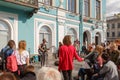 Musicians sing songs on the street in front of a crowd of passersby and tourists in sun spring day