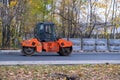 Articulated HAMM compact roller in bright orange on new asphalt paving