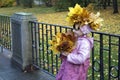 Cute girl in a wreath of yellow maple leaves posing