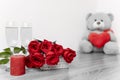 Saint Valentine`s day bouquet of roses, candle and teddybear