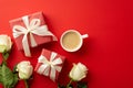 Top view photo of gift boxes with ribbon bows white roses and cup of fresh coffee on isolated red background Royalty Free Stock Photo