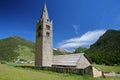 Sainte Cecile Church with Ceillac village, pine tree forests and mountain range covered with snow in the background,