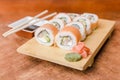 Sake roll with ginger, wasabi and soy sauce on a wooden table