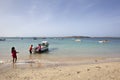 A local woman gives directions from the beach to two local men near a traditional fishing boat