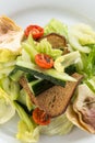 Salad with artichokes, cherry tomatoes, lettuce and rye bread on white plate close up