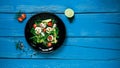 Salad of arugula, avocado, cheese, radish and cherry tomatoes on a black glossy plate Royalty Free Stock Photo