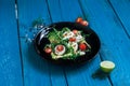 Salad of arugula, avocado, cottage cheese, radish and cherry tomatoes on a black glossy plate Royalty Free Stock Photo