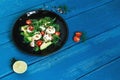 Salad of arugula, avocado, cottage cheese, radish and cherry tomatoes on a black glossy plate Royalty Free Stock Photo