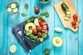 Salad with avocado, falafel, cucumber, cherry tomato and spinach on blue wooden background. Healthy vegan lunch bowl