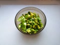 Salad with avocado and sesame seeds, oil is poured, on a wooden. Avocado salad in a plate, vegetarian food, green dietary salad