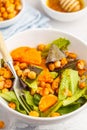 Salad with baked pumpkin and chickpeas with mustard-honey dressing in a white plate, macro. Healthy vegan food concept. Royalty Free Stock Photo