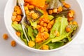 Salad with baked pumpkin and chickpeas with mustard-honey dressing in a white plate, macro. Healthy vegan food concept. Royalty Free Stock Photo