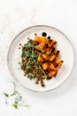 Salad with baked pumpkin, lentils and balsamic dressing garnished with peas microgreens on a light background.