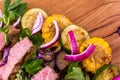 Salad with beef slices, grilled vegetables - eggplant, corn, mushrooms, sauce on a wooden board, dish Royalty Free Stock Photo