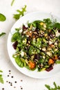 Salad with beetroot, avocado, feta cheese, rucola, tomato, various greens, pumpkin seeds in a white bowl. Diet healthy