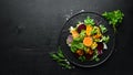 Salad: beetroot, pumpkin, corn and lettuce in a black plate on a black background. Top view.