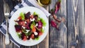 Salad of beets, lettuce, beetroot leaves, grapefruit and feta cheese on the old wooden background. Selective focus