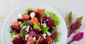 Salad of beets, lettuce, beetroot leaves, grapefruit and feta cheese on the old wooden background. Selective focus