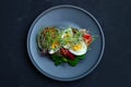 Salad of boiled eggs, herbs and tomatoes on a gray plate, top view. Royalty Free Stock Photo