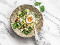 Salad for breakfast with couscous, avocado, spinach, mango, feta and boiled egg on a light background, top view