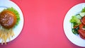 Salad, burger and french fries on white plates on pink background, fast food