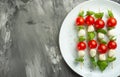 Salad Caprese - shish kebab with tomato, mozzarella and basil, Italian cuisine and a healthy vegetarian diet on a dark background.