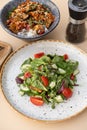 Salad with cherry tomatoes, cucumbers and arugula and bowl with tasty rice, meat and vegetables