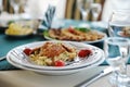 Salad with chiken on a white plate. Served on a table with a green tablecloth in a restaurant