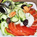 Salad cooked with sliced tomatoes, cucumbers and olives in a white plate