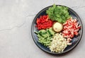 Salad of crab sticks, eggs, cucumber, bell pepper and lettuce on a dark round plate on a light gray background Royalty Free Stock Photo
