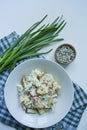 Salad with crackers, crab sticks, chicken fillet, fresh herbs and hard cheese seasoned with mayonnaise butter served in a white