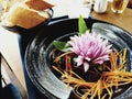 Salad dish with carrot stripes on a black plate with beautiful garnish, an onion rose, leaves of basil and baguette